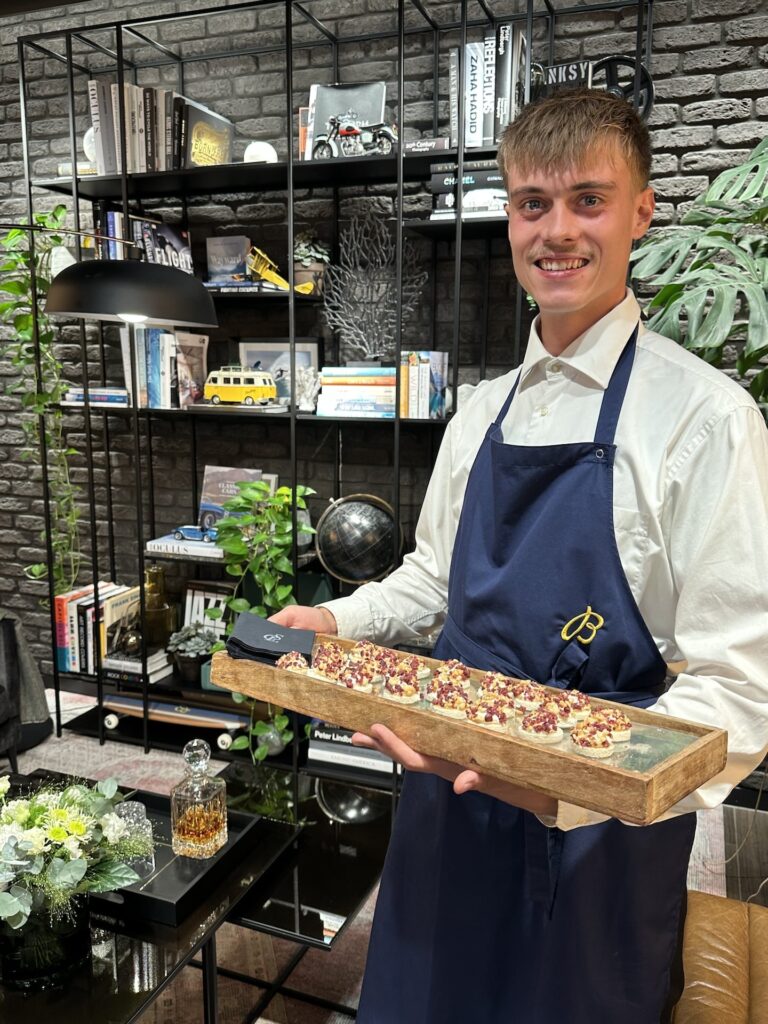 CSL Catering in München für Business und private Feiern 24 Ein Mitarbeiter von CSL Catering München hält ein Tablett mit ansprechend angerichteten Häppchen.